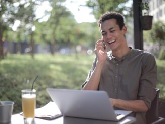 cheerful black male entrepreneur talking on smartphone in summer cafe