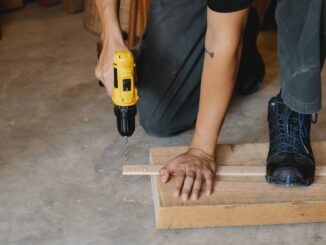 man drilling wooden plank in workshop - Taylor Swift named most popular artist for DIY projects in Spotify study