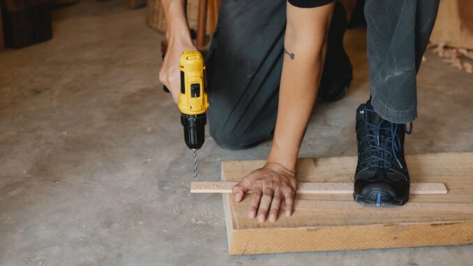 man drilling wooden plank in workshop - Taylor Swift named most popular artist for DIY projects in Spotify study