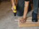 man drilling wooden plank in workshop - Taylor Swift named most popular artist for DIY projects in Spotify study