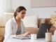 thoughtful woman with earbuds using laptop