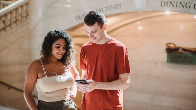 positive young multiethnic couple browsing smartphone during trip in new york - Six Social media trends you will be obsessed with in 2021
