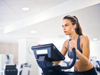 What are the 10 most popular gym songs? - young female athlete training alone on treadmill in modern gym
