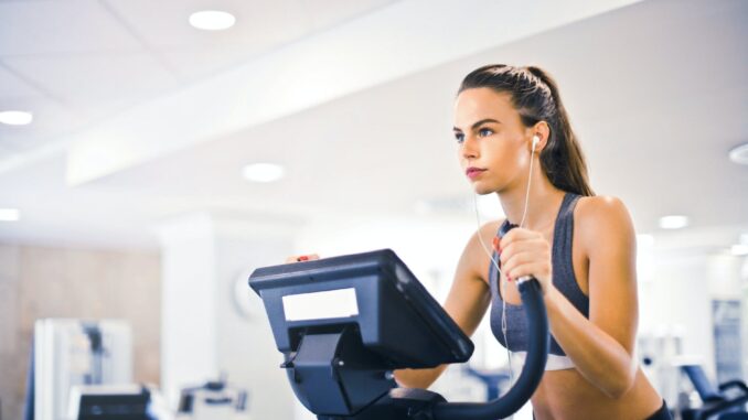 What are the 10 most popular gym songs? - young female athlete training alone on treadmill in modern gym