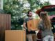 couple passing carton box to each other while unpacking car