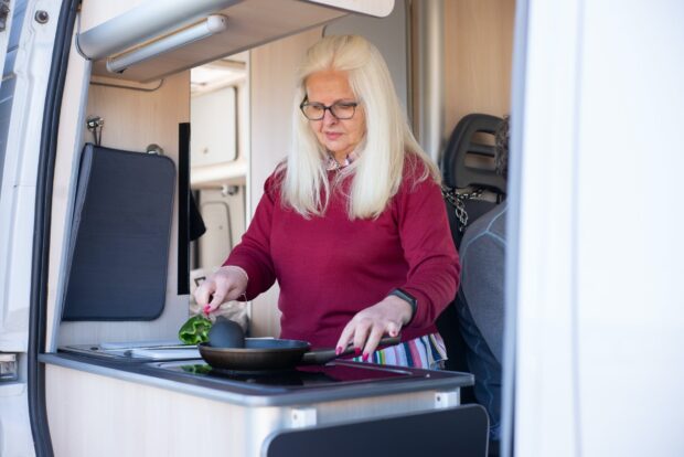 woman in red long sleeve shirt holding black tray - caravan holiday
