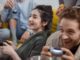 smiling woman in black shirt holding silver smartphone - Research Reveals The Nationalities That Cheat The Most At Video Games