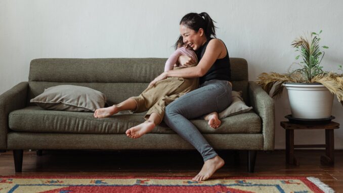 photo of woman sitting on couch while hugging her child