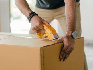 crop man taping carrying box with scotch - Downsizing Checklist: Steps To Staying Organized While Moving