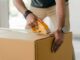 crop man taping carrying box with scotch - Downsizing Checklist: Steps To Staying Organized While Moving