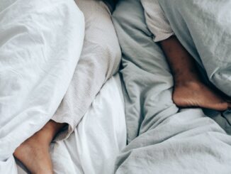 crop anonymous person lying in bed - duvet hogging