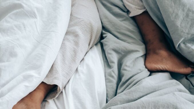 crop anonymous person lying in bed - duvet hogging