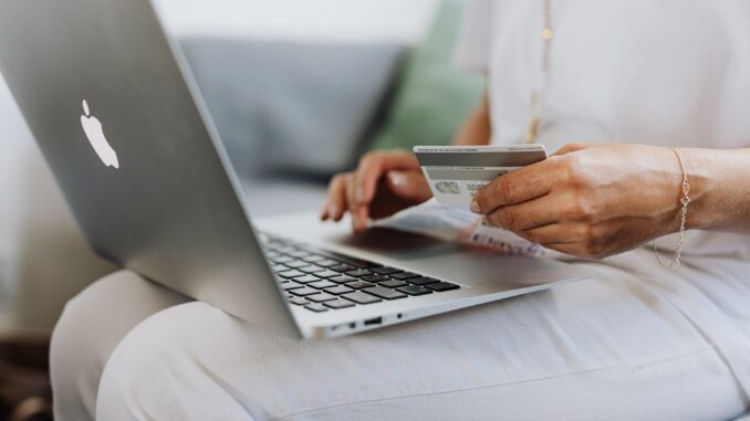 online shopping leads to overspending - person using a macbook and holding a credit card