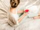 9 Things to do to Unwind after a Stressful Day - aerial view photography of woman sitting on blanket while holding mug filled with pink liquid looking sideward