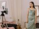woman in a green dress looking at her cellphone in a tripod - How To Make £4,000 From Stuff You Have At Home