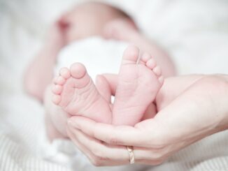 close up of hands holding baby feet - Study reveals the best baby names according to astrology