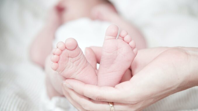 close up of hands holding baby feet - Study reveals the best baby names according to astrology