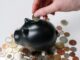 person putting coin in a piggy bank - Experts reveal how to talk to your partner about money