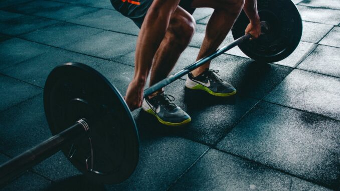 person holding barbell - Study Reveals The UK Cities That Take The Most Gym Selfies
