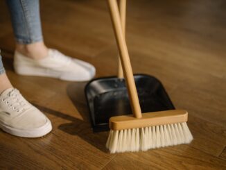household cleaning tasks - person wearing white pants and white socks standing beside brown broom