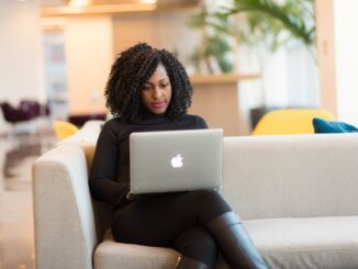 woman using macbook sitting on white couch