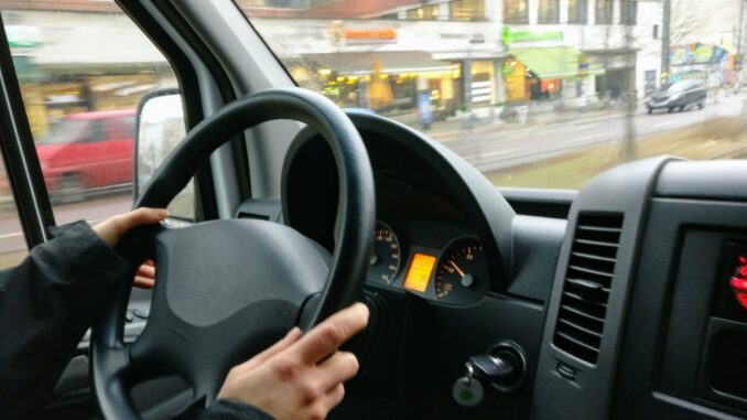 person holding steering wheel of car