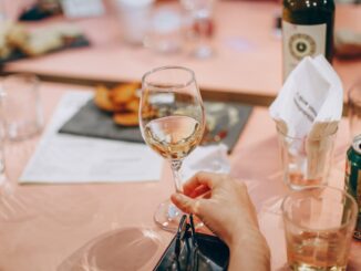 person holding wine glass near clear shot glasses